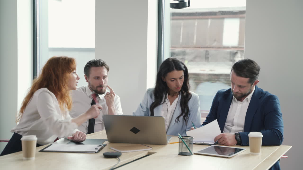 Business meeting between two women and two businessmen. One of the parts hands over a contract to sign and the other part does it.