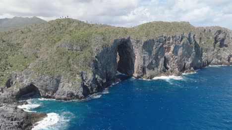 dramatic cave, rock formation hole in steep clips at ocean coastline, aerial