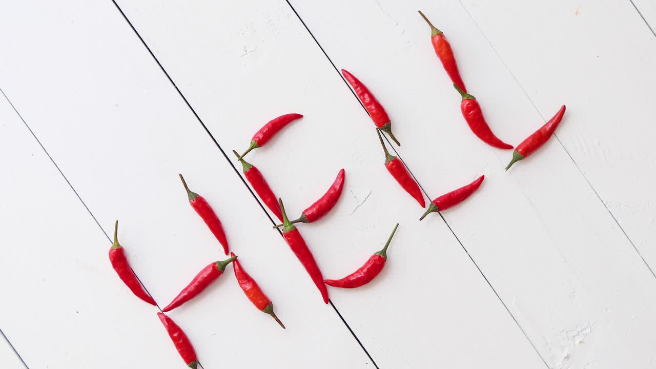 흰색 나무 테이블에 놓인 작은 빨간 고추로 형성된 단어 지옥