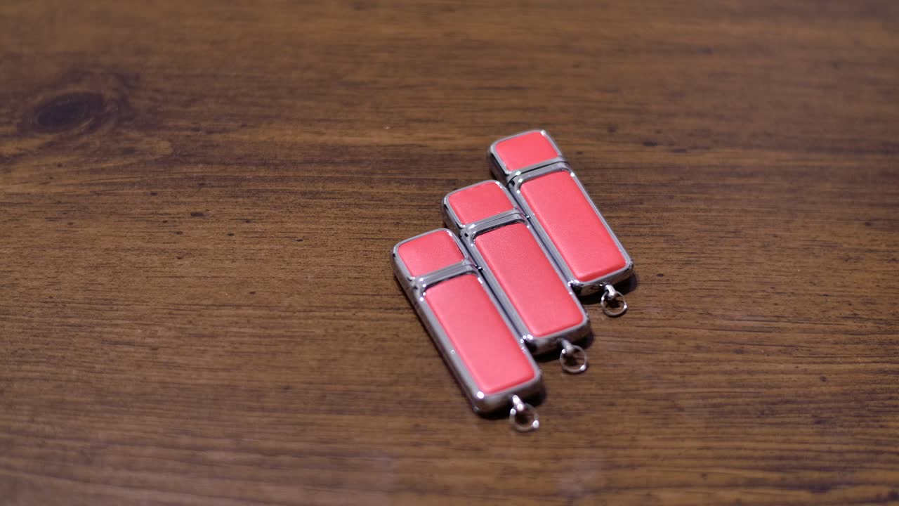 Rightward parallax shot of pink USB drives on wood, with shallow depth of field.
