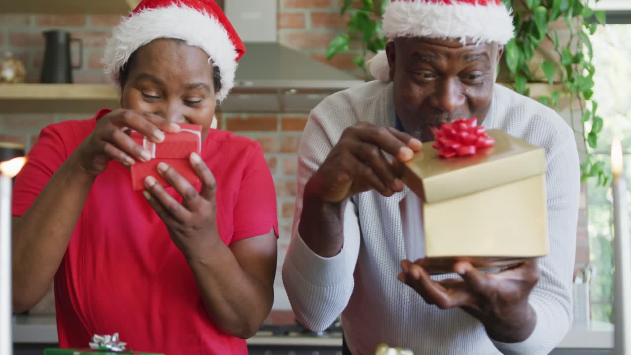 feliz pareja de ancianos afroamericanos en sombreros de santa con regalos en videollamada en tiempo de navidad