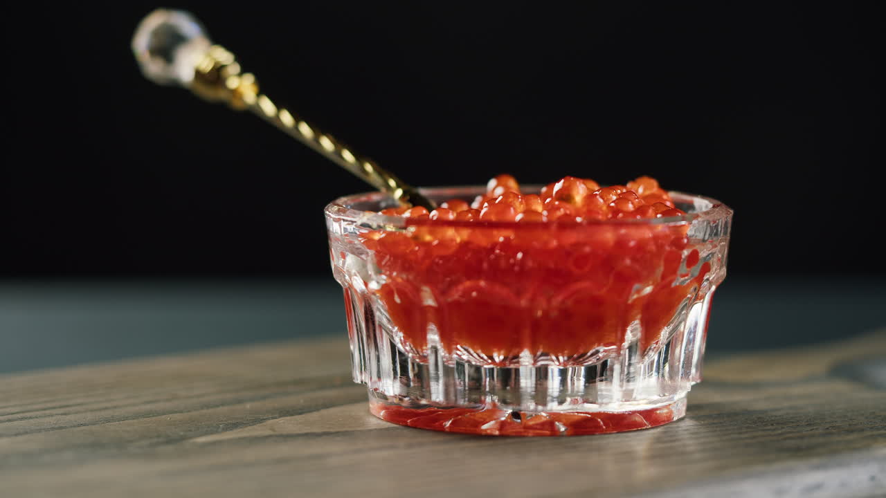 Servire caviale rosso da una ciotola di vetro con un cucchiaio