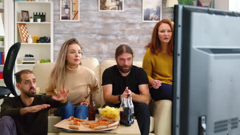 two couples cheering up while watching a football match on tv