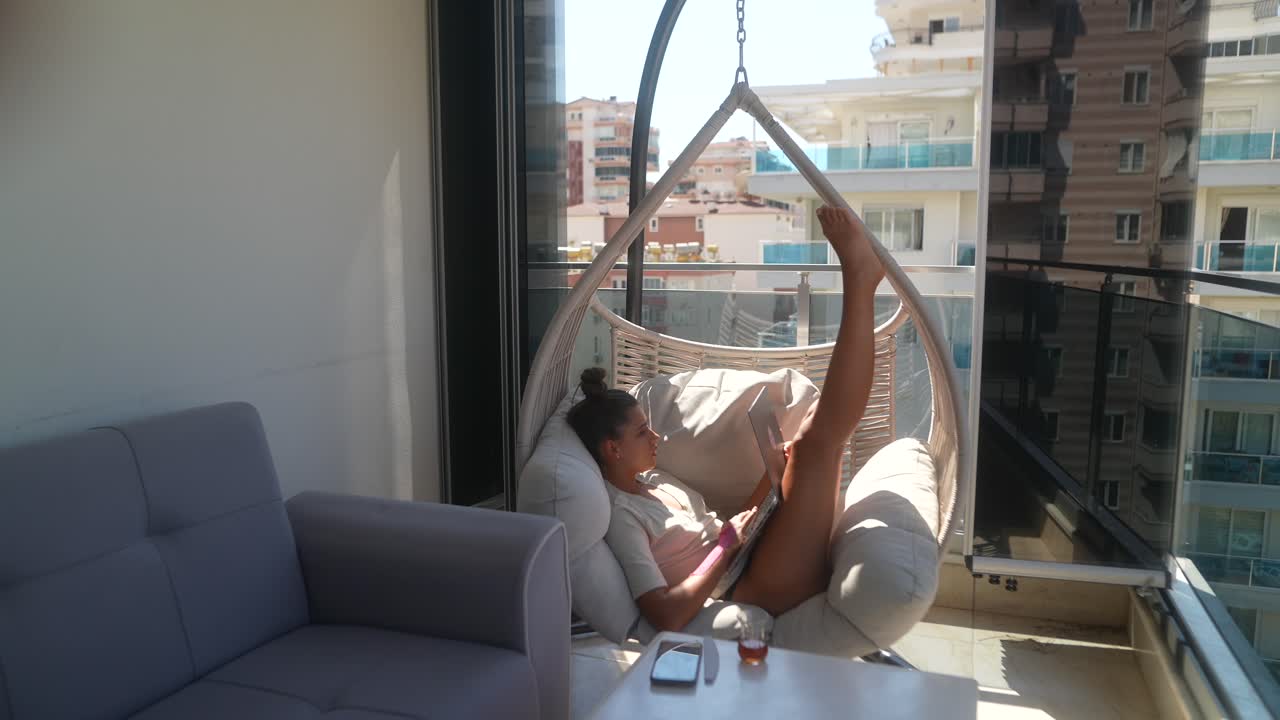 mujer trabajando en una computadora portátil en el balcón