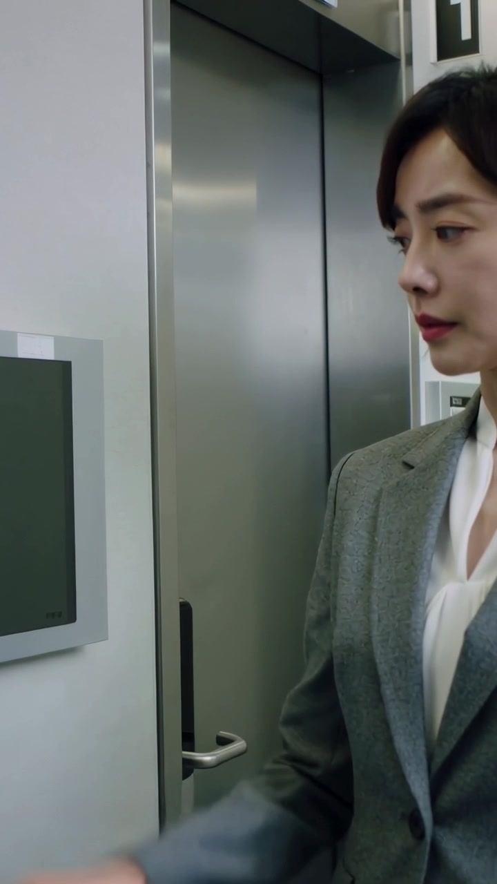 Vertical video: Tapping woman in suit pressing panel in hall, calling lift and waiting, copy space