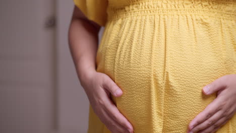 clutching and stroking her bulging baby bump, the expectant pregnant woman is feeling the movement of the baby in her stomach