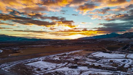 sunset and colorful cloudscape above picturesque mountains and a highway running through the valley - aerial hyperlapse