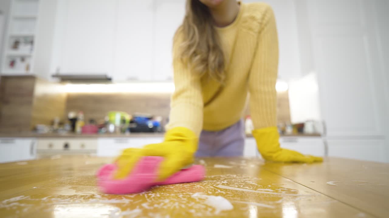 Una mujer usa un paño de microfibra para limpiar y pulir una superficie, capturando la limpieza del hogar, la higiene, la limpieza de primavera y el cuidado meticuloso del hogar en un ambiente doméstico.