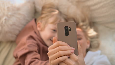 madre e hijo mintiendo tomando un selfie con un teléfono inteligente