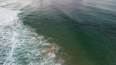 Sea-surfers-laying-on-surfboard-floating-on-ocean-waiting-for-wave