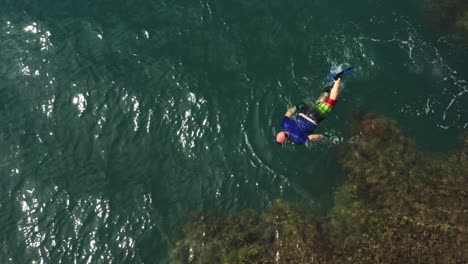 Aerial-view-above-scuba-diver-in-flippers-exploring-Panama-coral-reef-tropical-blue-sea-coastline