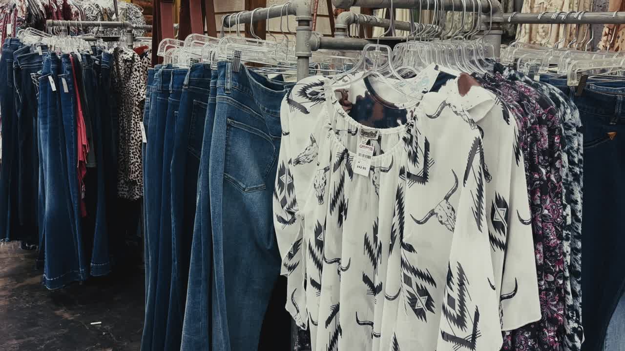 Estantería con vaqueros azules y tops con estampados del Oeste expuestos en una tienda de ropa de Texas