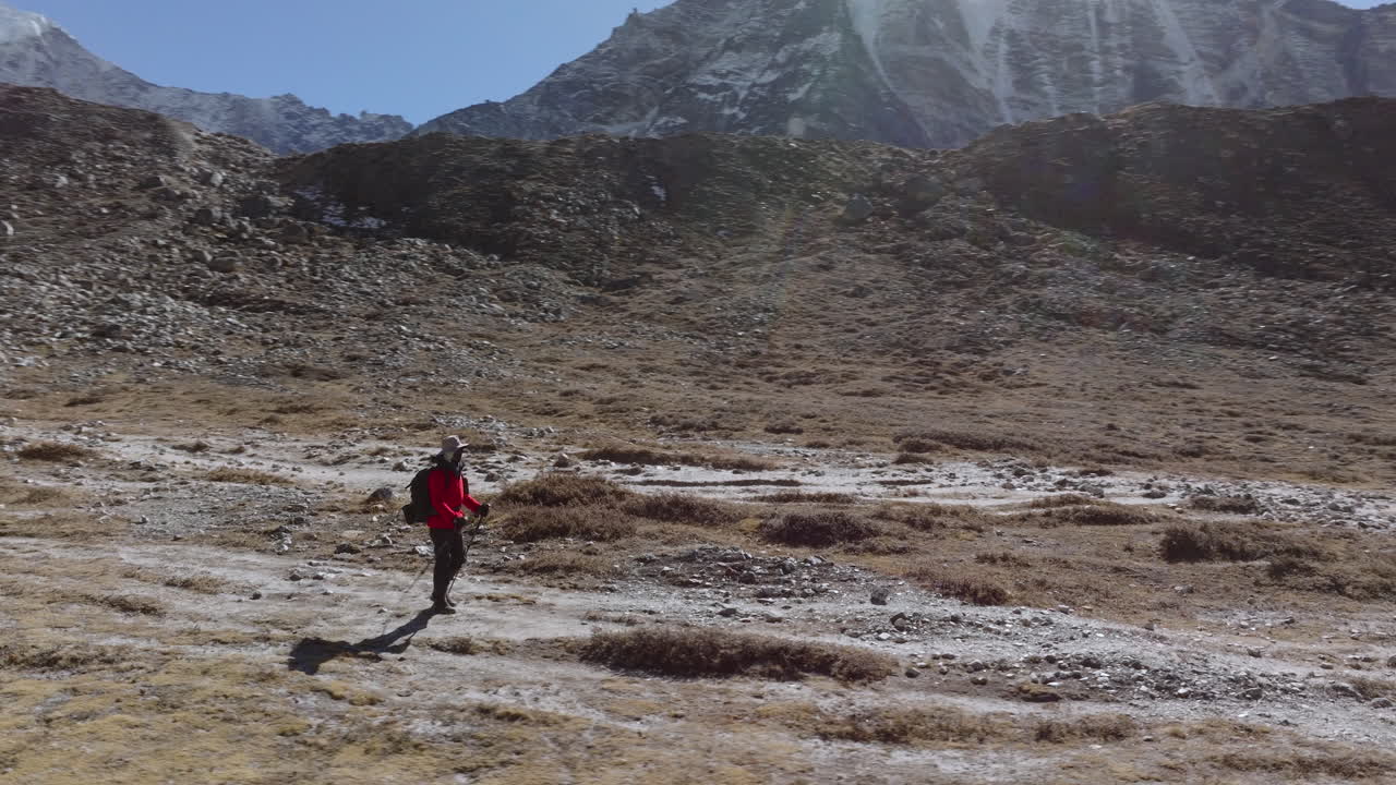 Hiker Walking Through a Vast Mountain Valley Towards Snow-Capped Peaks