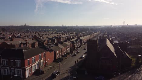 Aerial-view-reveals-rows-of-historic-terraced-houses-orbiting-over-long-road-leading-towards-the-bustling-town-centre