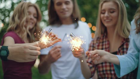 happy friends with sparklers having fun outdoors