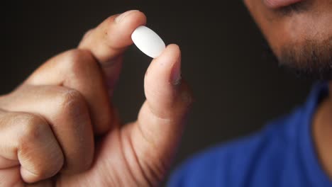 a man holds a white pill in his hand