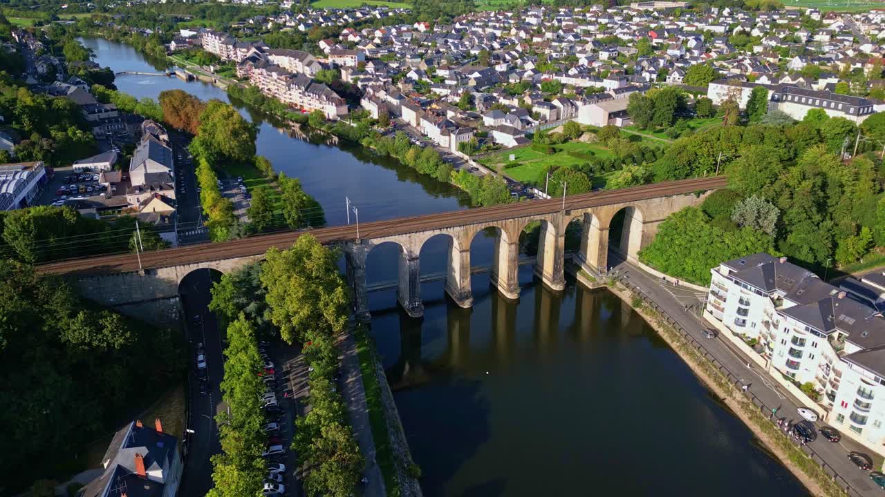 Aerial of Laval viaduct bridge over Mayenne River with buildings greenery, drone pullback