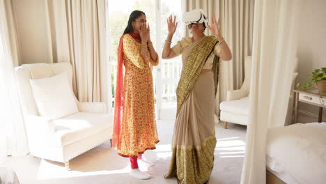 using vr headset, indian woman in traditional indian sari with friend in living room