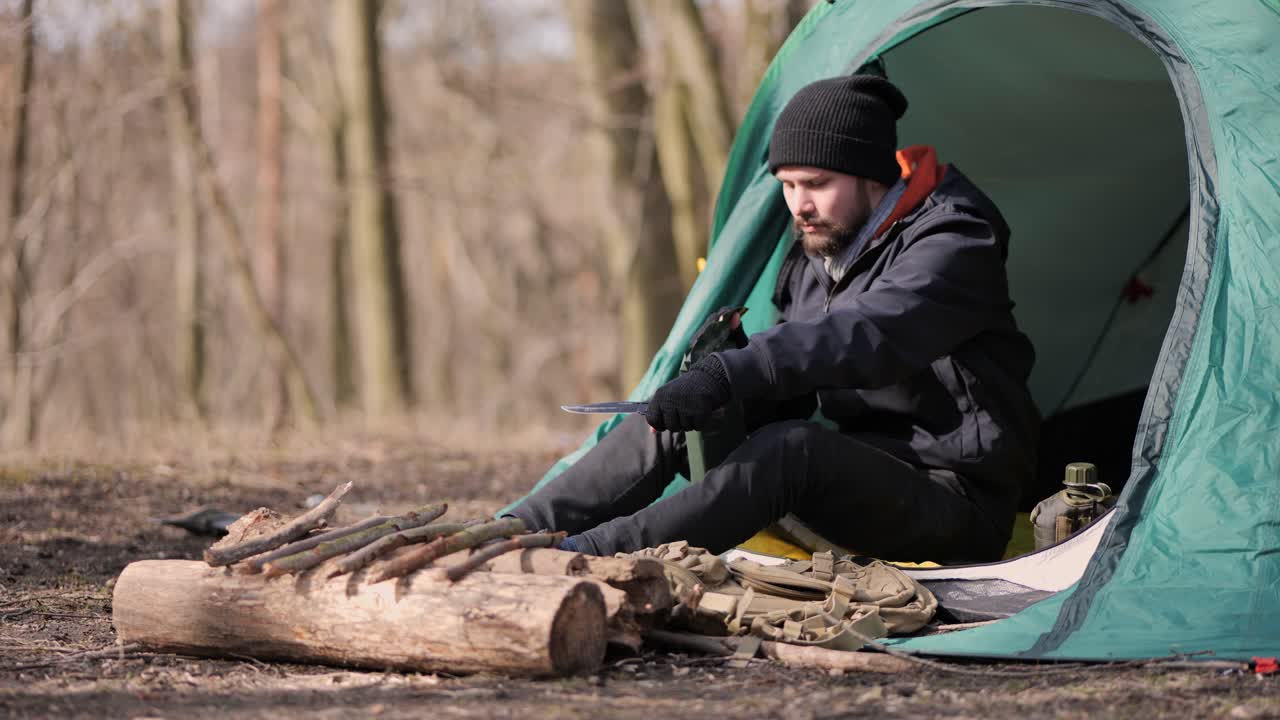 Portrait of traveller opening MRE food ration in camping tent in wilderness