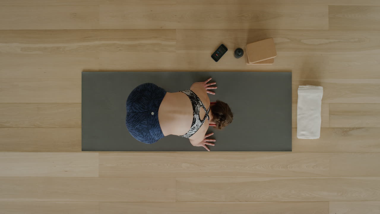 vista superior de una mujer de yoga practicando una pose de loto hacia adelante en un estudio de ejercicios disfrutando de un estilo de vida saludable, practicando meditación en una colchoneta de ejercicios.