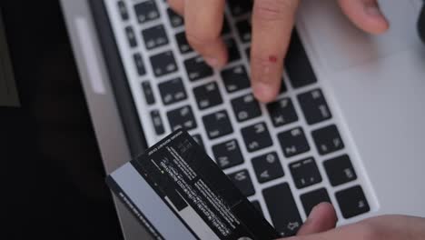 Ausgeschnittene-Aufnahme-Männlicher-Hände,-Die-Eine-Kreditkarte-Halten-Und-Auf-Der-Tastatur-Eines-Laptops-Tippen