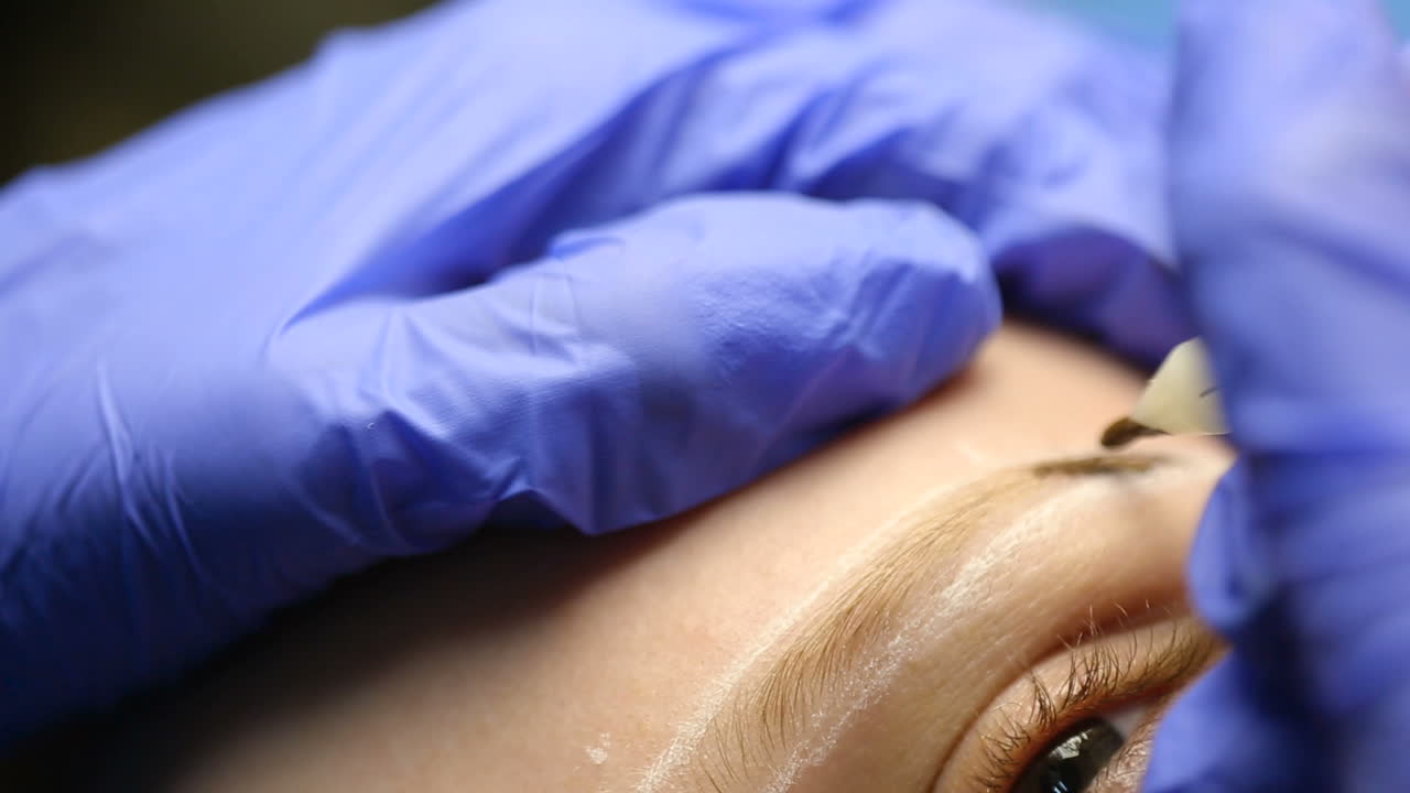 Correction of eyebrows. Young woman having permanent makeup eyebrow in beautician salon