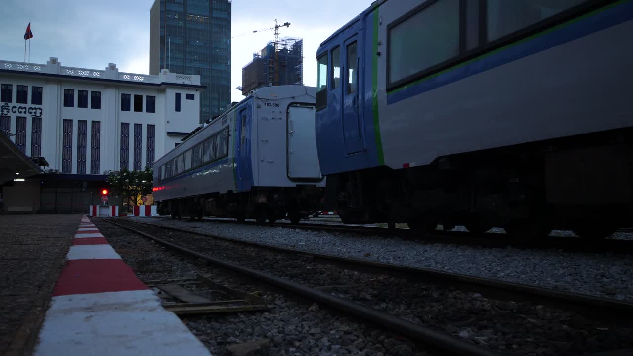 Modern blue trains at Phnom Penh railway station with city buildings in background