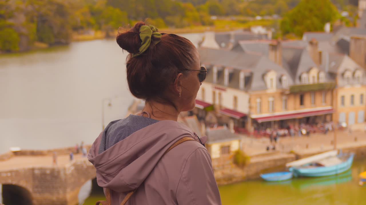 A young female tourist views the picturesque and tranquil port of Saint Goustan, Brittany