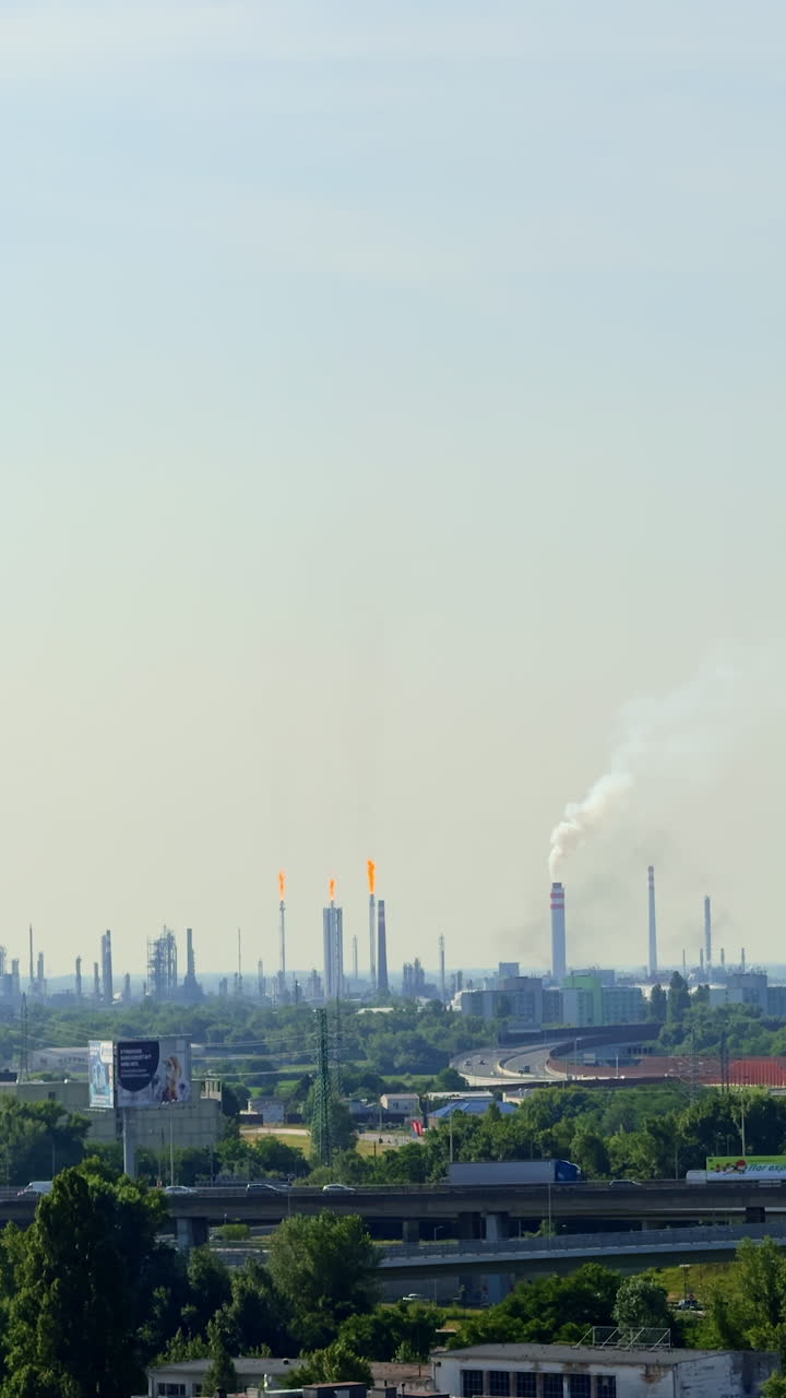Smokestacks in skyline. A vast industrial area with tall smokestacks and flares highlights active manufacturing under a clear sky