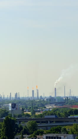 smokestacks in skyline. a vast industrial area with tall smokestacks and flares highlights active manufacturing under a clear sky