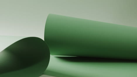 close up of green rolled pieces of paper on white background with copy space in slow motion