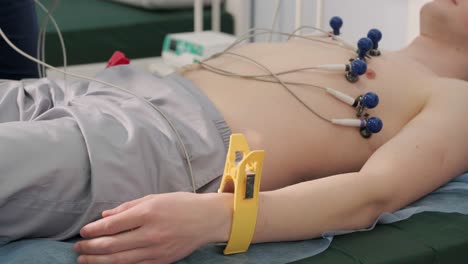 cardiac examination in a hospital with a professional cardiograph. the patient lies on a bed with connected sensors.