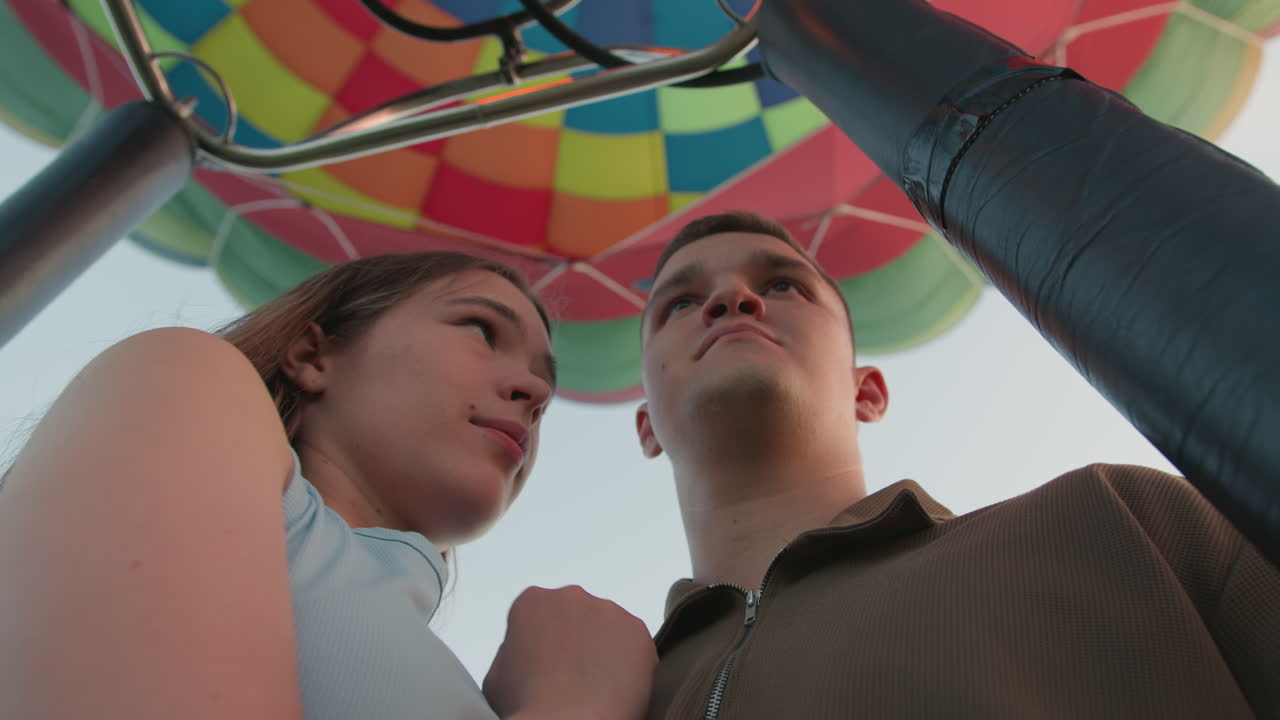 close up of romantic couple embracing under vibrant hot air balloon canopy with peaceful expressions as woman rests her head on man shoulder sharing intimate moment