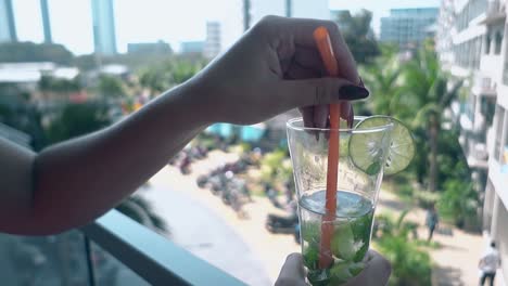 mujer sostiene una bebida y disfruta de una hermosa vista desde el balcón del hotel
