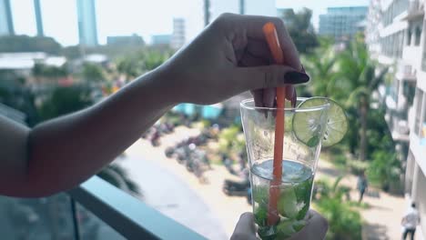 woman holds beverage and enjoys nice view from hotel balcony