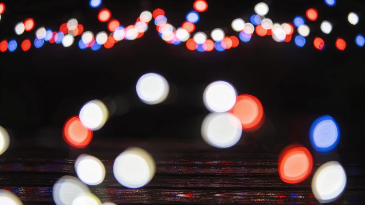 Moving blurred lights drifting and pulsing at night from camera shake, with bright garland on plank