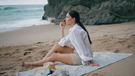 Niña-Comiendo-Picnic-En-La-Playa-De-Manzana-Sentada-En-Una-Manta.-Mujer-Disfruta-De-La-Fruta-Verticalmente