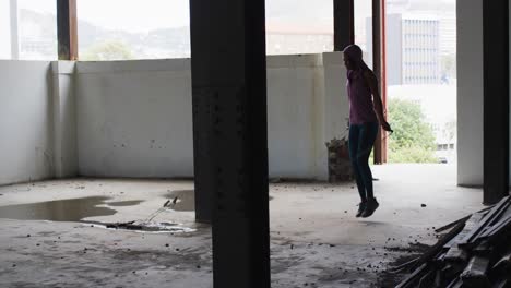 african american woman wearing hoodie skipping with rope in an empty urban building