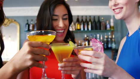 Young-women-toasting-cocktail-glasses-at-bar-counter