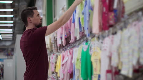 man shopping for baby clothes in a store