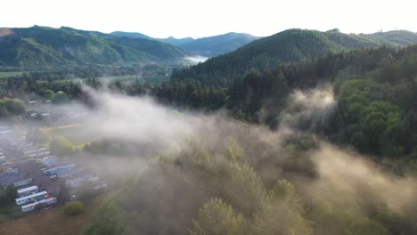 Aerial-View-of-Fog-Above-Campground,-Evergreen-Forest-and-Landscape-Near-Forks-City,-Washington-State