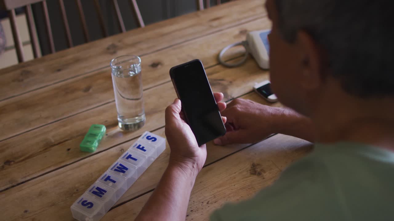 hombre de raza mixta senior que tiene una consulta médica en línea usando un teléfono inteligente