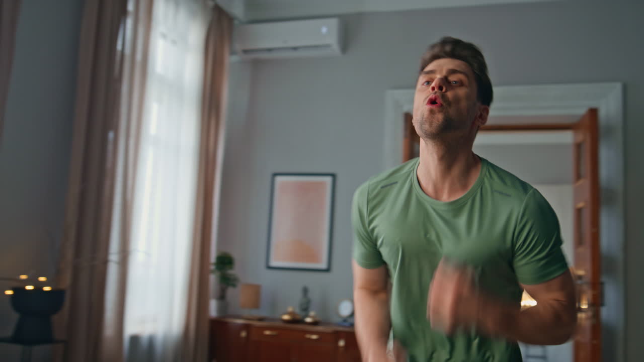 Energetic sportsman exercising home close up. Enthusiastic young man jumping