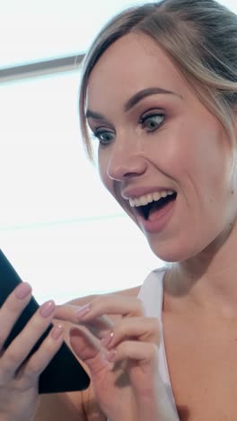 a joyful young woman happily smiling while using her smartphone outdoors, surrounded by vibrant greenery and nature