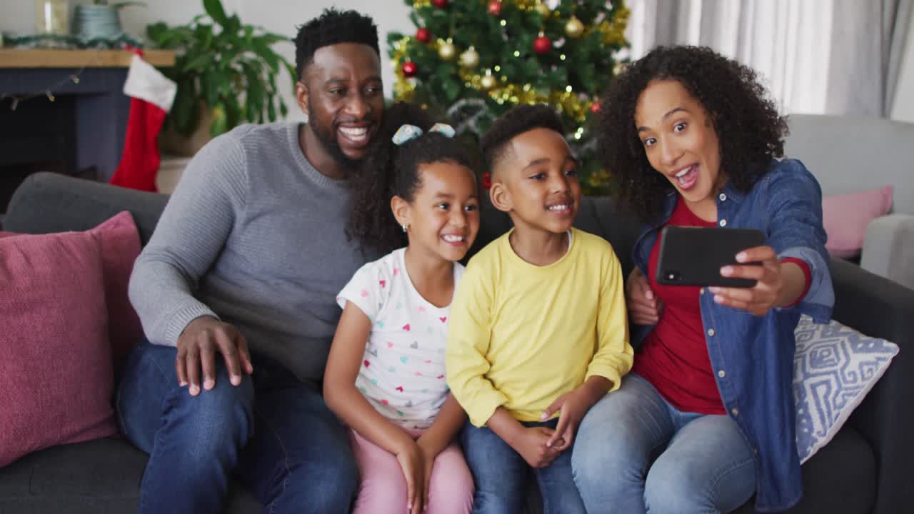 Smiling african american family taking selfie, christmas decorations in background