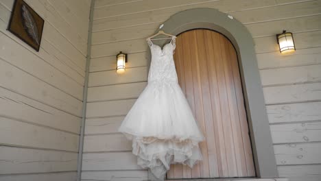 Elegant-wedding-dress-hanging-in-the-arched-door-way-of-a-wood-sided-guest-house-at-Le-Belvédère-in-Wakefield,-Quebec,-Canada