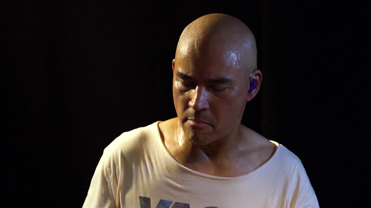 Close up of a drummer while he is playing his instrument and sweating a lot