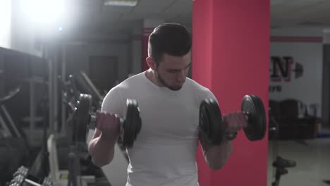 a fitness trainer lifts two dumbbells for getting bigger biceps and good deltoids