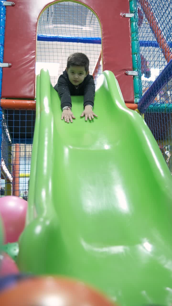 Little boy riding on slide in entertainment center