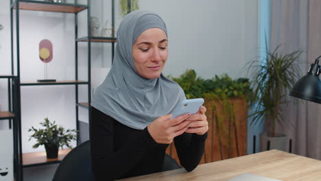 Muslim-woman-share-messages-on-smartphone-social-media-applications-online,-watching-relax-movie